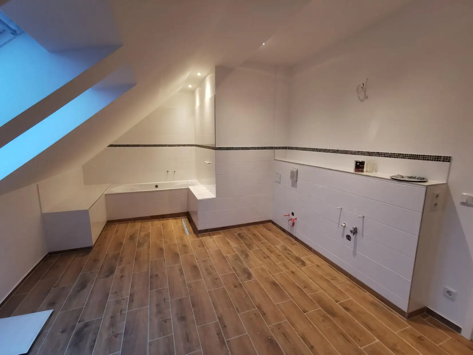 Neues Bad unter der Dachschräge mit Wanne und Fliesen in Holzoptik