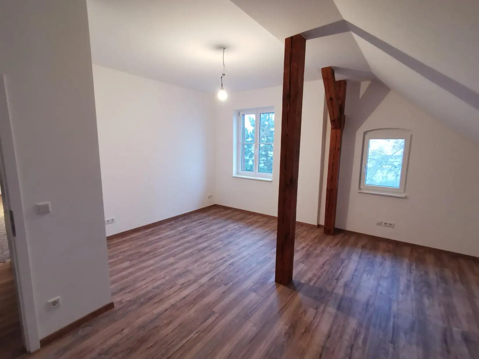 Ausgebautes Zimmer im Dachgeschoss Roskow mit freigelegten Holzbalken und neuem Boden