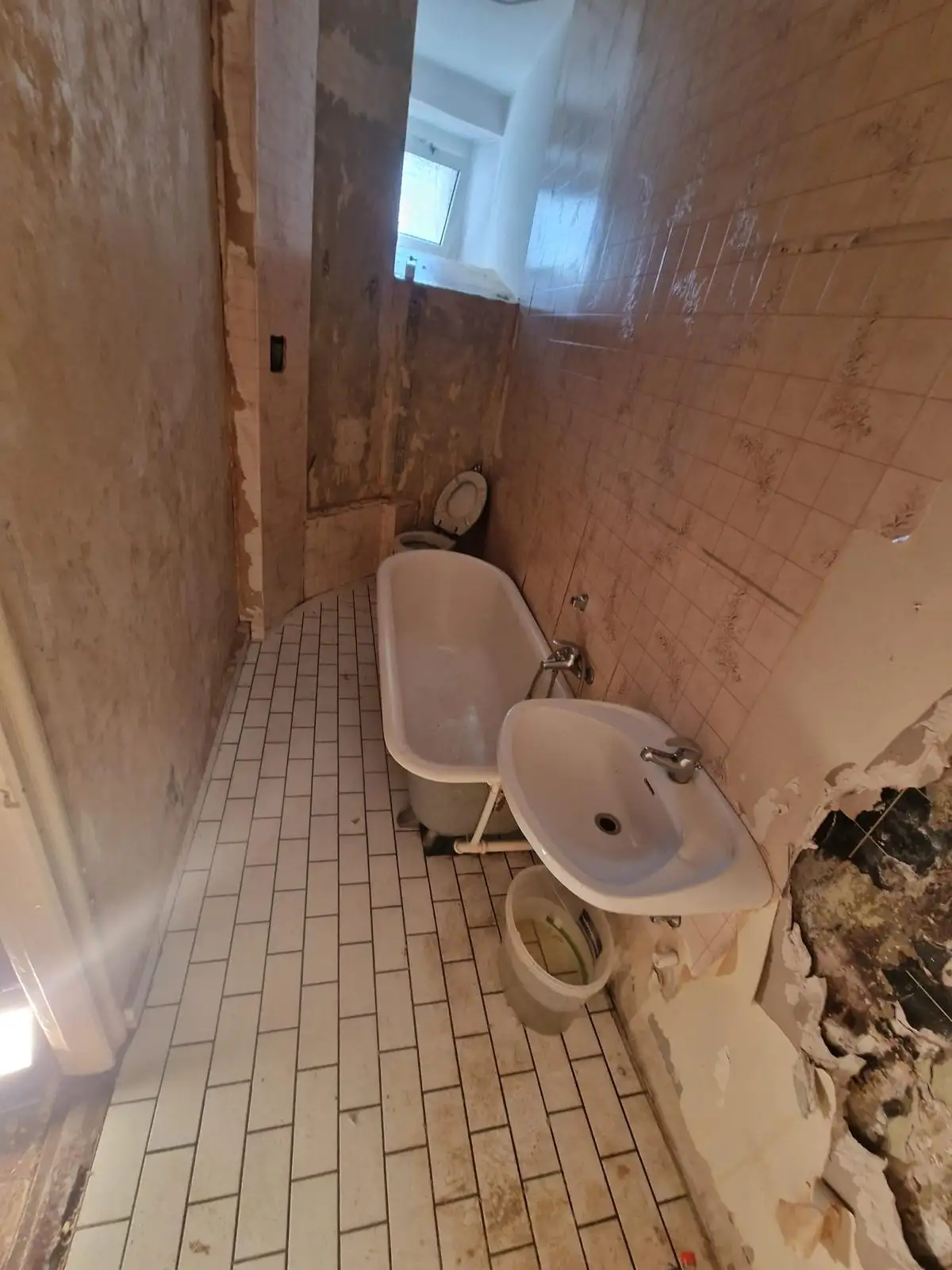 Bad vor der Sanierung – alte Wanne, beschädigte Fliesen und Wände