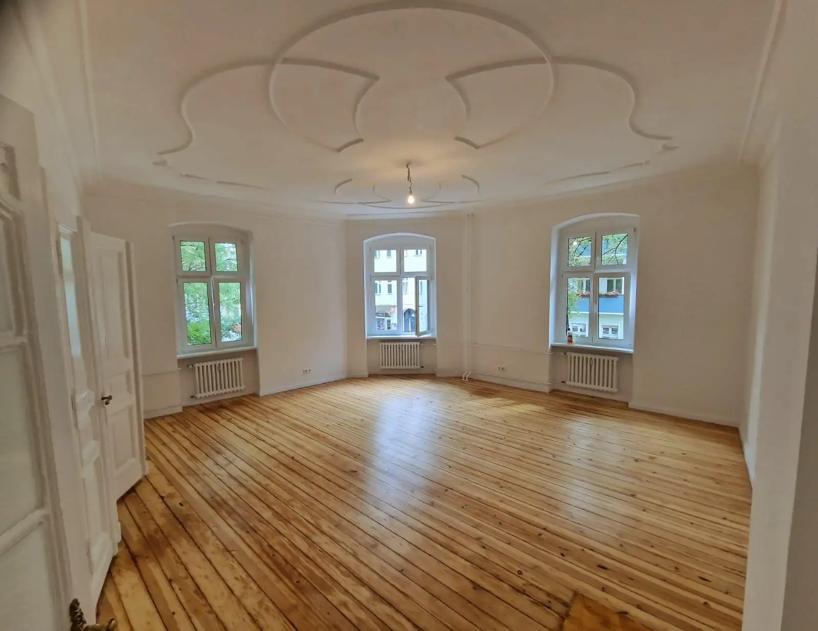 Altbausanierung in Berlin-Schöneberg – sanierter Altbauraum mit Stuckdecke und Dielenboden
